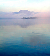 Misty hills over a still lake.