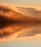 Misty hills reflected in water.