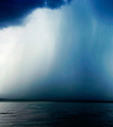 Rain streaming from dark clouds over water.