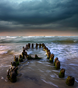 A wooden dock leading out into a stormy bay.