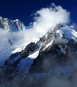 Snow blowing from high mountain peaks.